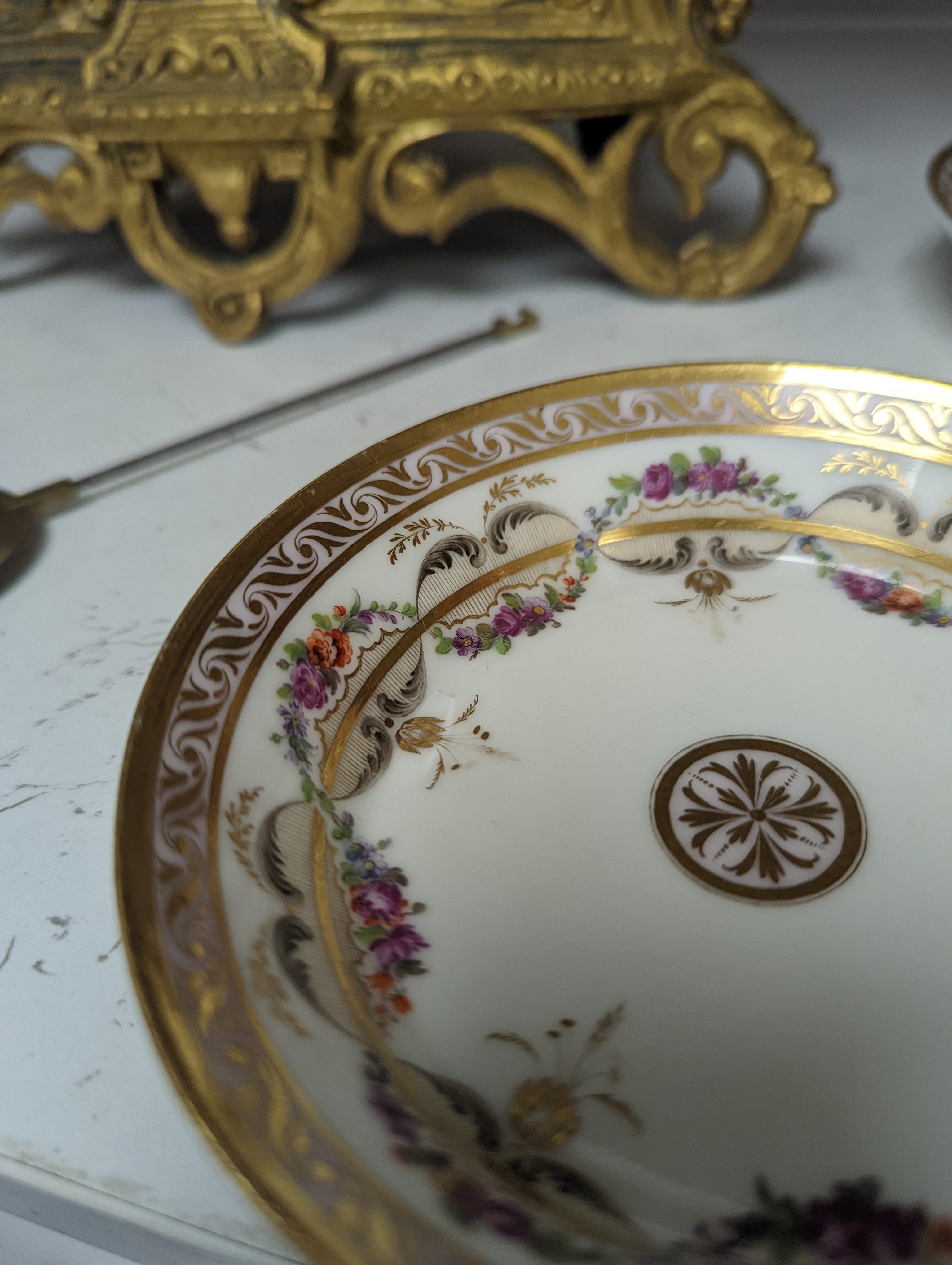 A Duc d'Angouleme coffee can and saucer painted with a puce chain of leaves on a salmon coloured ground and another painted with a flower chain, black feather and a gilt line, latter with stencilled red mark 'Manuf de M